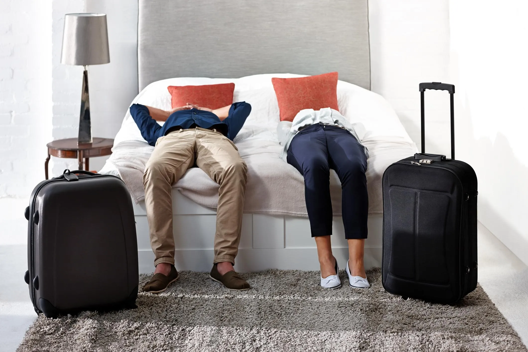 uomo e donna distesi sul letto con valigie al rientro dalle vacanze